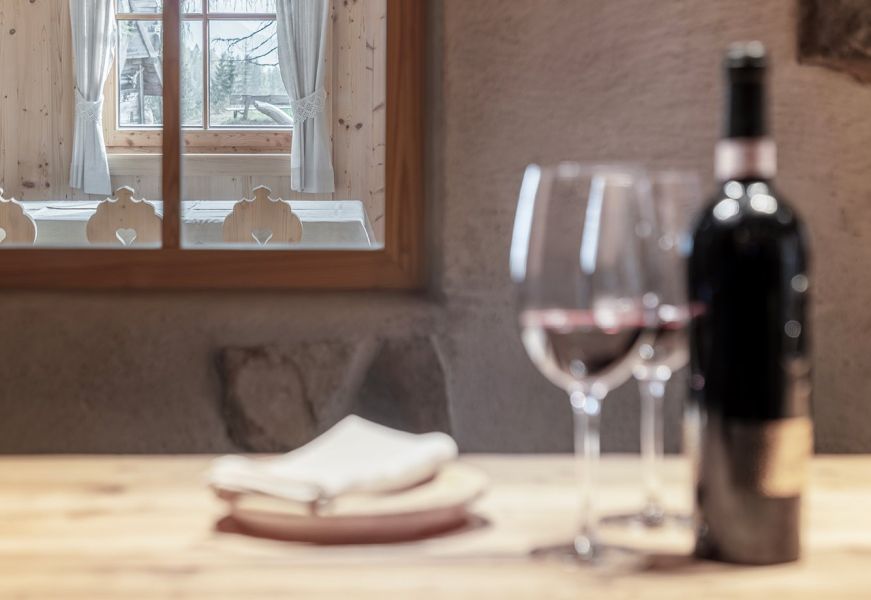 Dettaglio della stube del Rifugio Ütia Lé con vino rosso sfocato in primo piano