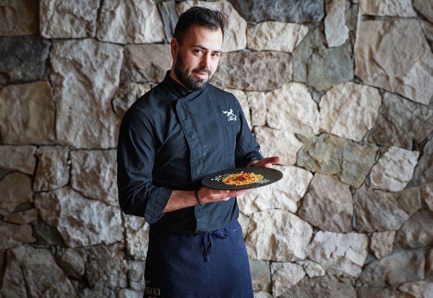 Chef del rifugio con divisa nera presenta un piatto gourmet